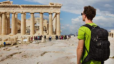 Student with backpack on looking at ruins.