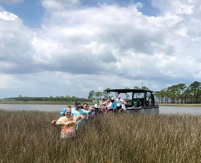 Marine sciences students out on a boat and in the marsh working.