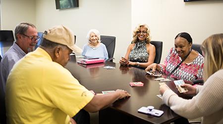 Elderly people smiling around table.